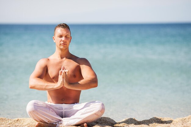 Jeune homme méditant sur la plage.