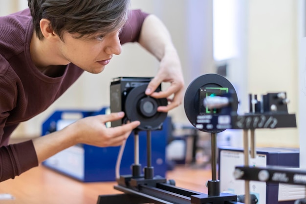 un jeune homme mène des expériences avec une loupe en verre ou une lentille optique b