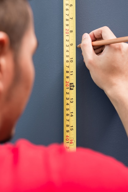 Jeune homme mesurant avec un ruban à mesurer