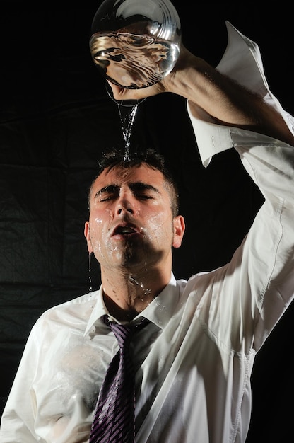 Photo un jeune homme met de l'eau sur son visage sur un fond noir.