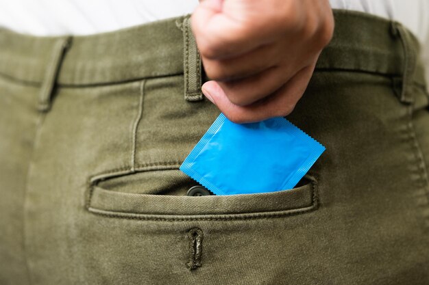 Un jeune homme met un préservatif dans la poche de son pantalon pour se préparer à l'utiliser Campagne pour des rapports sexuels protégés et la contraception