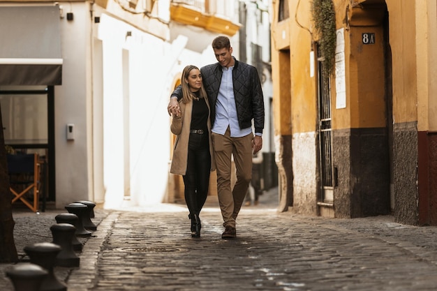 Un jeune homme met son bras autour de sa petite amie alors qu'ils marchent dans les rues d'une ville ancienne