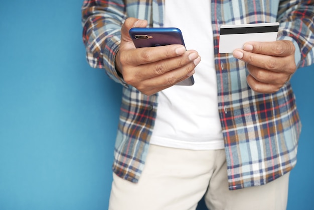Jeune homme mettant les détails de la carte de crédit sur un téléphone intelligent