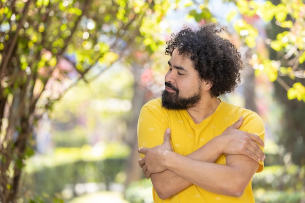 Jeune homme mexicain avec barbe et afro se serrant dans ses bras concept d'amour de soi