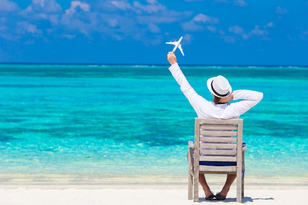 Jeune homme avec miniature d'un avion sur une plage tropicale