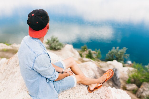 Jeune homme à la mode assis près de la mer