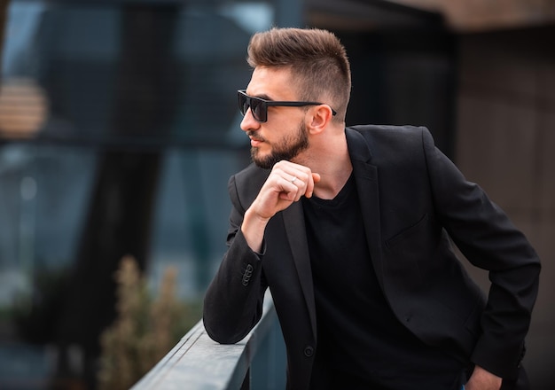 Un jeune homme à la mode heureux posant à l'extérieur