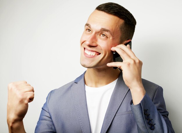 Un jeune homme à la mode parle au téléphone portable sur un fond blanc.