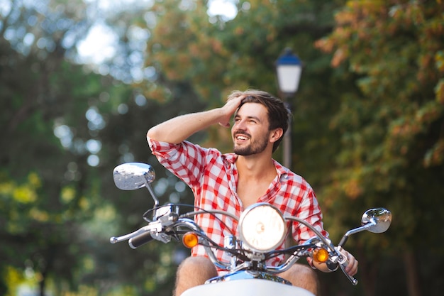 Jeune homme à la mode sur un scooter vintage