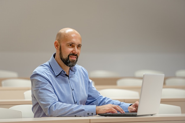 Jeune homme moderne sur une conférence universitaire travaillant sur un ordinateur portable