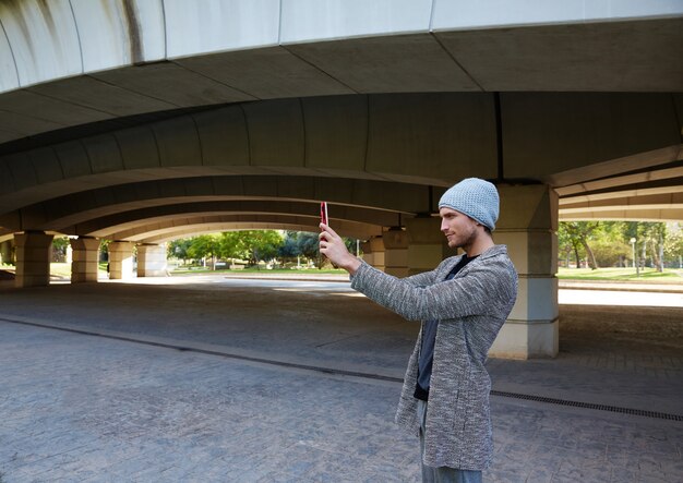 Jeune homme moderne avec tablette sous un pont