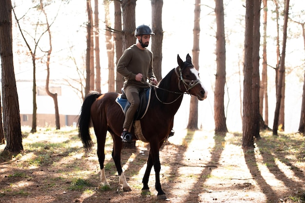 Jeune homme monte un cheval portant un casque