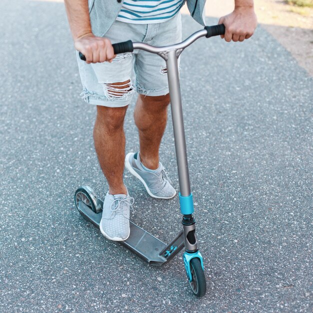 Jeune homme monté sur un scooter moderne par une chaude journée d'été