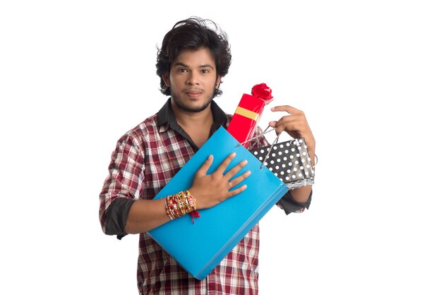 Jeune homme montrant rakhi sur sa main avec des sacs à provisions et une boîte-cadeau à l'occasion du festival Raksha Bandhan.