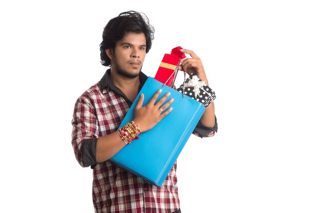Jeune homme montrant rakhi sur sa main avec des sacs à provisions et une boîte-cadeau à l'occasion du festival Raksha Bandhan.