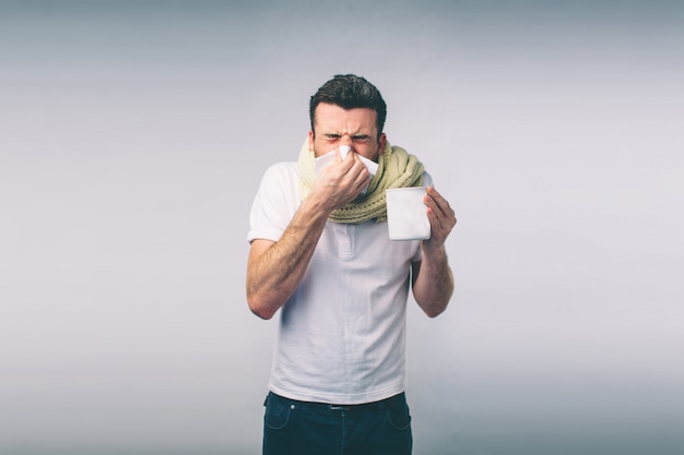 jeune homme avec un mouchoir. Un malade isolé a le nez qui coule. l'homme fait un remède contre le rhume.Nerd porte des lunettes.