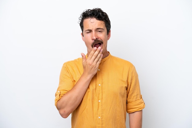 Jeune homme à la moustache isolé sur fond blanc bâillonnant et couvrant la bouche grande ouverte avec la main