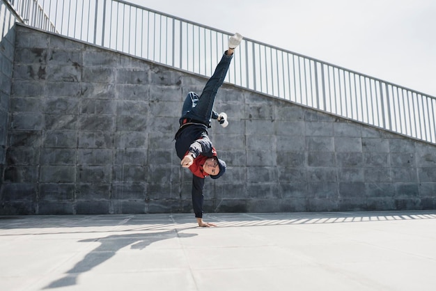 Un jeune homme en mouvement acrobatique libre dans la rue de la ville, beau exercice physique