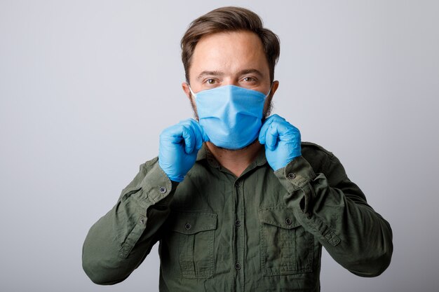 Jeune homme sur un mur blanc dans un masque médical sur son visage qui protège contre les coronavirus et autres maladies.