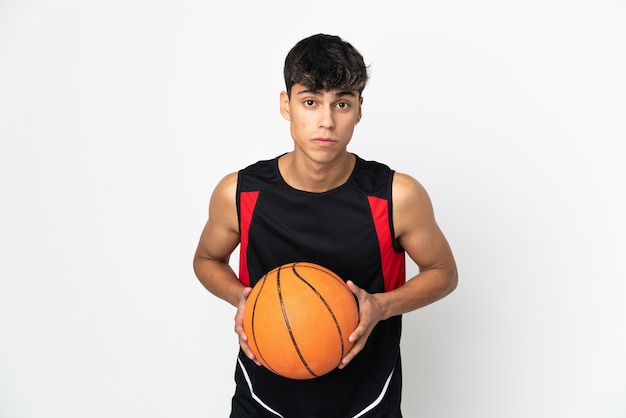 Jeune homme sur un mur blanc isolé jouant au basket