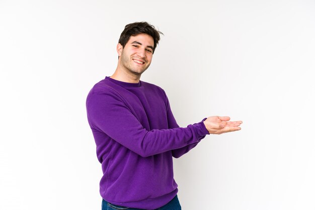 Jeune homme sur un mur blanc, tenant un espace vide sur une paume.