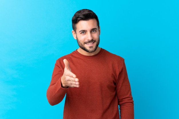 Jeune homme sur mur bleu isolé