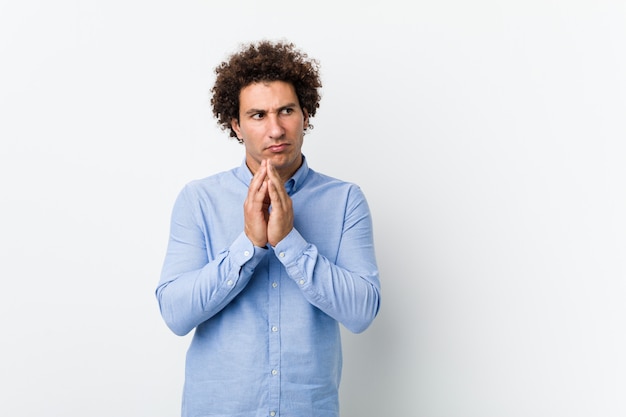 Jeune homme mûr bouclé portant une chemise élégante, établissant un plan à l'esprit, mettant en place une idée.