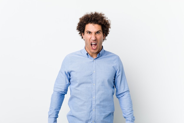 Photo jeune homme mûr et bouclé, vêtu d’une élégante chemise hurlant très en colère et agressive.