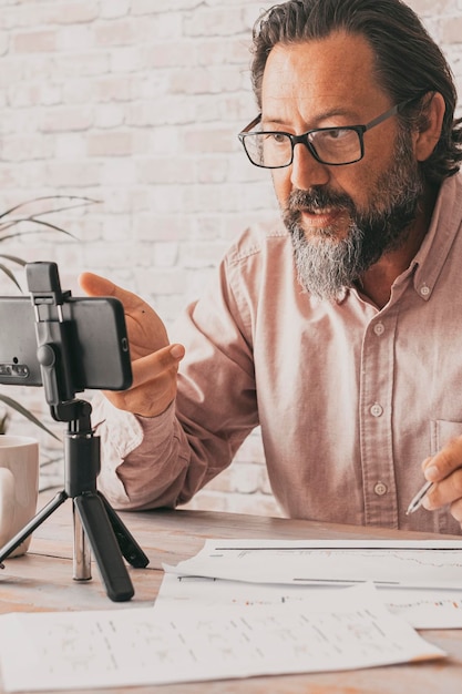 Jeune homme mûr utilisant un téléphone portable pour enregistrer une leçon en ligne pour sa chaîne Créateur de contenu, activité de style de vie Personnes adultes avec un travail moderne Appareil cellulaire et créateur de contenu travaillant