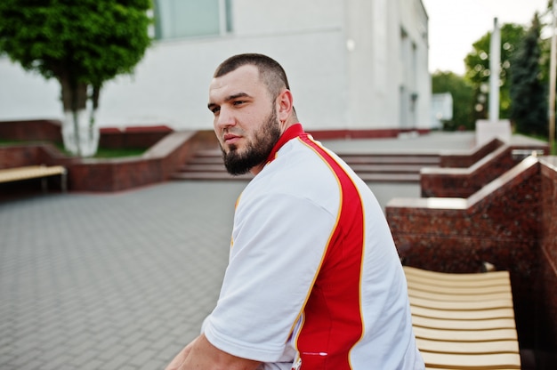 Jeune homme musclé barbu porter un costume de sport blanc avec une chemise rouge