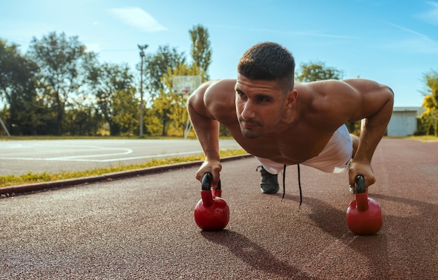 Jeune homme musclé caucasien travaillant avec des haltères