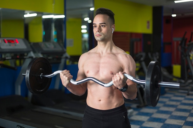 Jeune homme musclé effectuant des exercices avec des poids pour les biceps