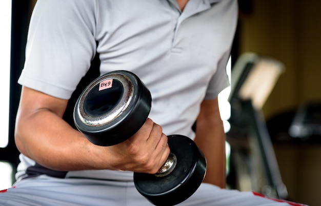 Jeune homme musclé faisant un exercice de poids lourd pour les biceps avec des haltères