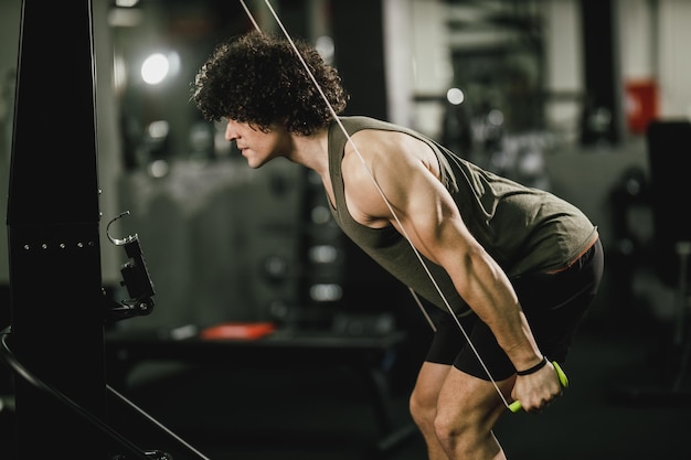 Un jeune homme musclé fait de l'entraînement crossfit à la corde de ski dur dans la salle de sport.