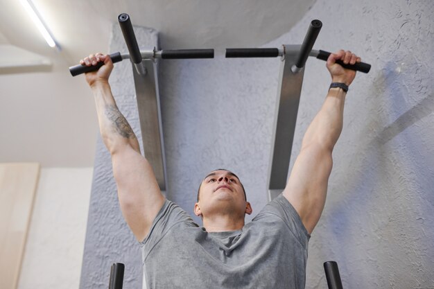 Jeune homme musclé fort dans la salle de gym, homme exerçant, faisant des tractions