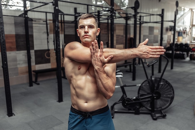 Jeune homme musclé pratiquant l'étirement musculaire dans un club de santé moderne