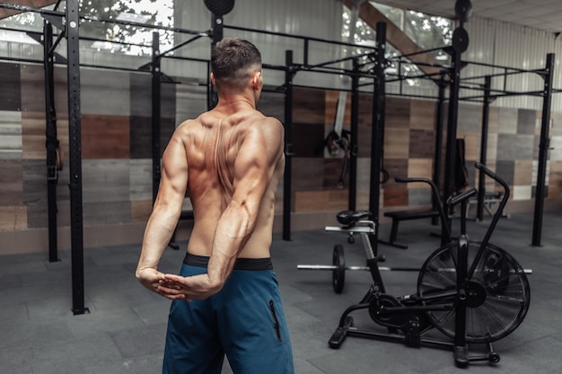 Jeune homme musclé pratiquant l'étirement musculaire dans un club de santé moderne