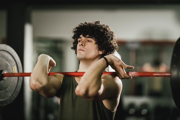 Photo un jeune homme musclé s'entraîne dur avec des haltères au gymnase.