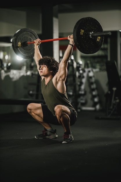 Un jeune homme musclé s'entraîne dur avec des haltères au gymnase.