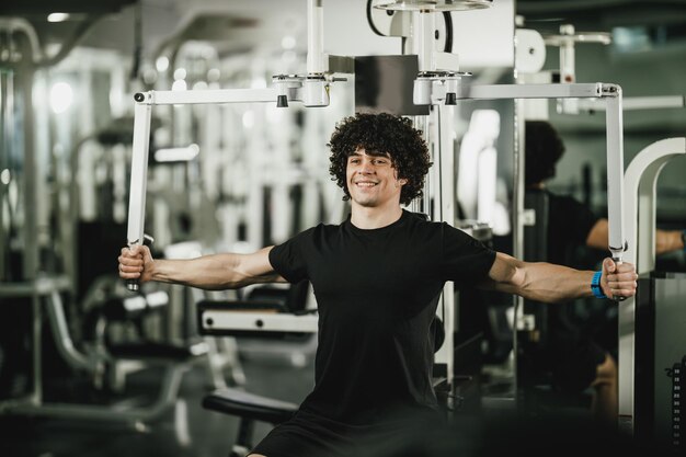 Un jeune homme musclé s'entraîne sur une machine dans la salle de sport.