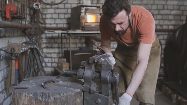 Jeune homme musclé travaillant sur un forgeron avec métal, grand angle