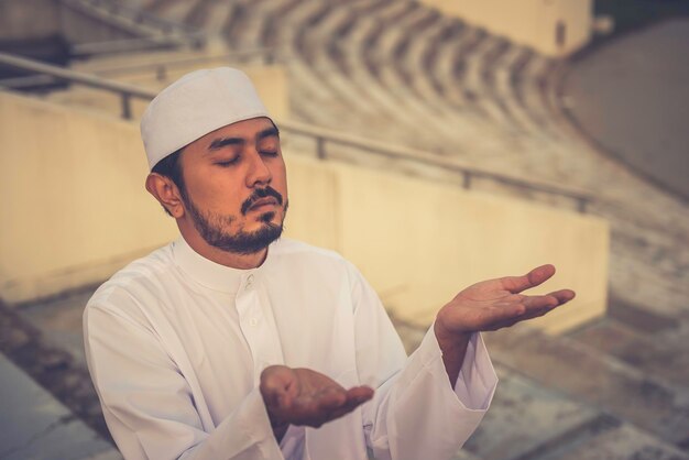 Un jeune homme musulman asiatique priant sur le concept du festival du ramadan au coucher du soleil