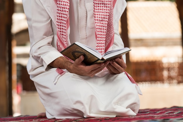 Jeune homme musulman faisant la prière traditionnelle à Dieu tout en portant une casquette traditionnelle Dishdasha