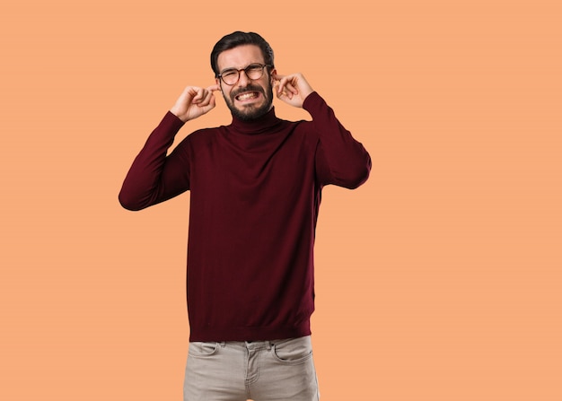 Jeune homme naturel couvrant les oreilles avec les mains