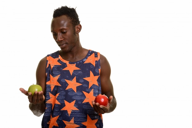 Jeune homme noir africain choisissant entre pomme verte et rouge