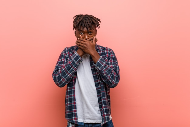 Jeune homme noir africain choqué couvrant la bouche avec les mains.