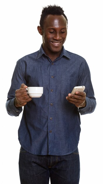 Jeune homme noir africain heureux souriant et tenant une tasse de café