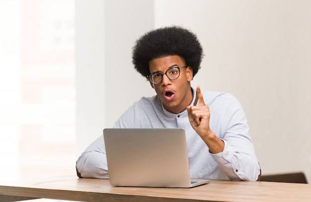 Jeune homme noir à l&#39;aide de son ordinateur portable ayant une idée, un concept d&#39;inspiration