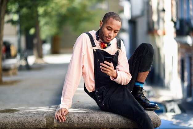 Jeune homme noir à l&#39;aide d&#39;un téléphone intelligent à l&#39;extérieur