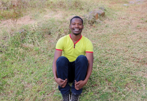 Un jeune homme noir assis sur l'herbe